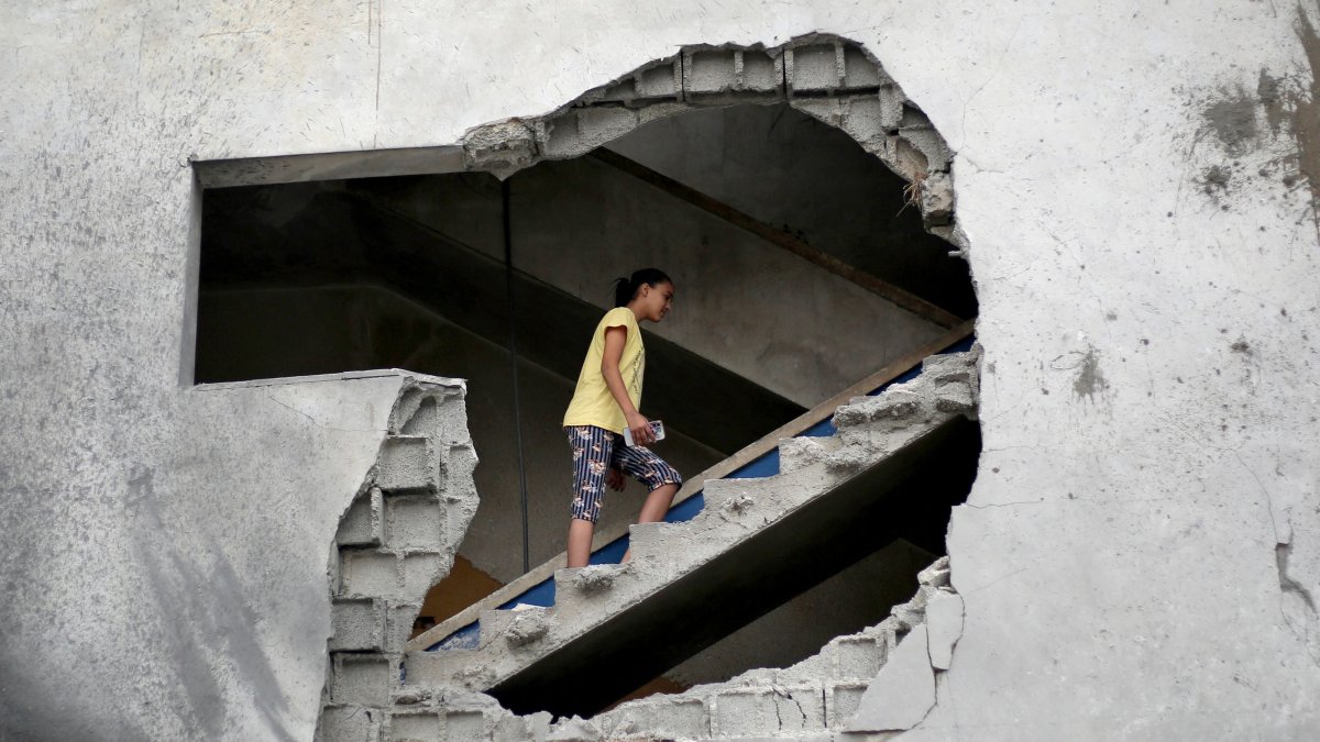 A woman is seen through a gaping hole as she walks up a set of stairs to inspect the site of a house targeted in an Israeli airstrikes in al-Zawayda, central Gaza Strip, Oct. 11, 2026. (AFP Photo)