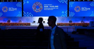 People stand in front of a display featuring the logo of the IMF-World Bank Group Annual Meetings 2026 during preparations for the event at the Queen Sirikit National Convention Center, Bangkok, Thailand, Oct. 9, 2026. (AFP Photo)