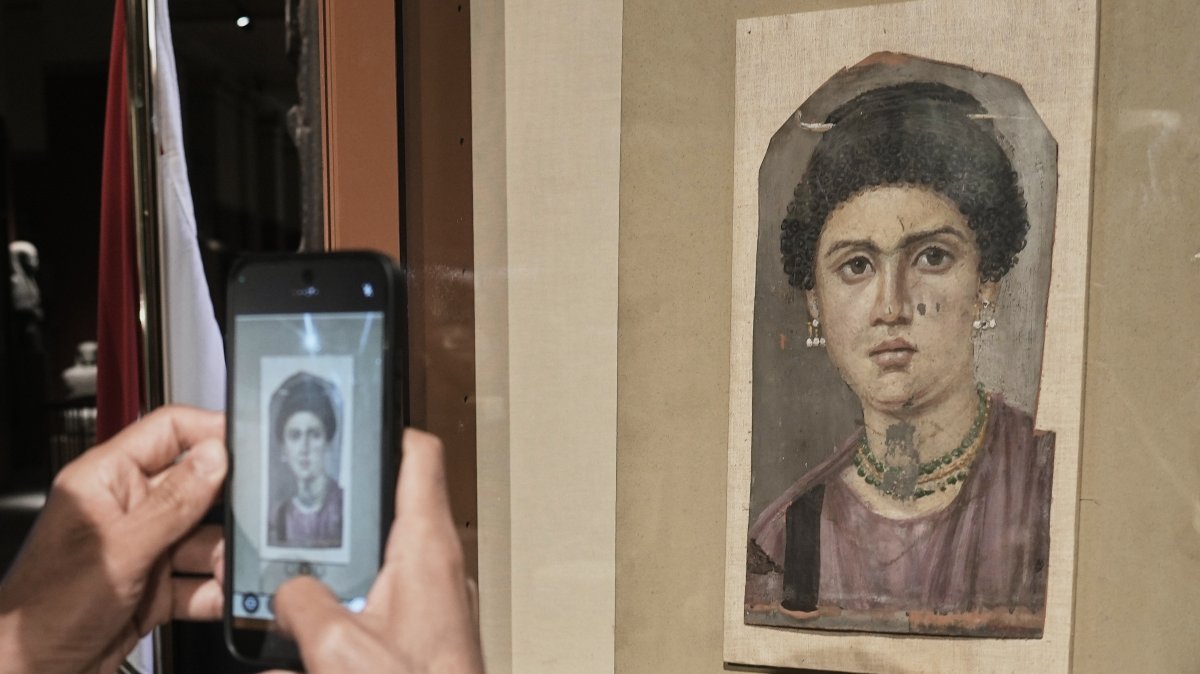 A visitor photographs one of the Fayoum portraits, "Demos," from the Greco-Roman period, at the Egyptian Museum, Cairo, Egypt, Oct. 11, 2026. (AP Photo)