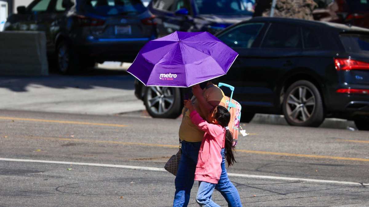 People walk while covering themselves with an umbrella during an extreme heat warning, Los Angeles, California, U.S., Oct. 6, 2026. (AFP Photo)