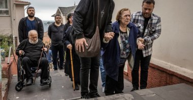 Elderly people are helped on the stairs at a school used as a polling station in front of the Bosporus, Istanbul, Türkiye, May 28, 2023. (Getty Images Photo)
