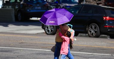 People walk while covering themselves with an umbrella during an extreme heat warning, Los Angeles, California, U.S., Oct. 6, 2026. (AFP Photo)