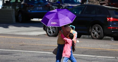 People walk while covering themselves with an umbrella during an extreme heat warning, Los Angeles, California, U.S., Oct. 6, 2026. (AFP Photo)