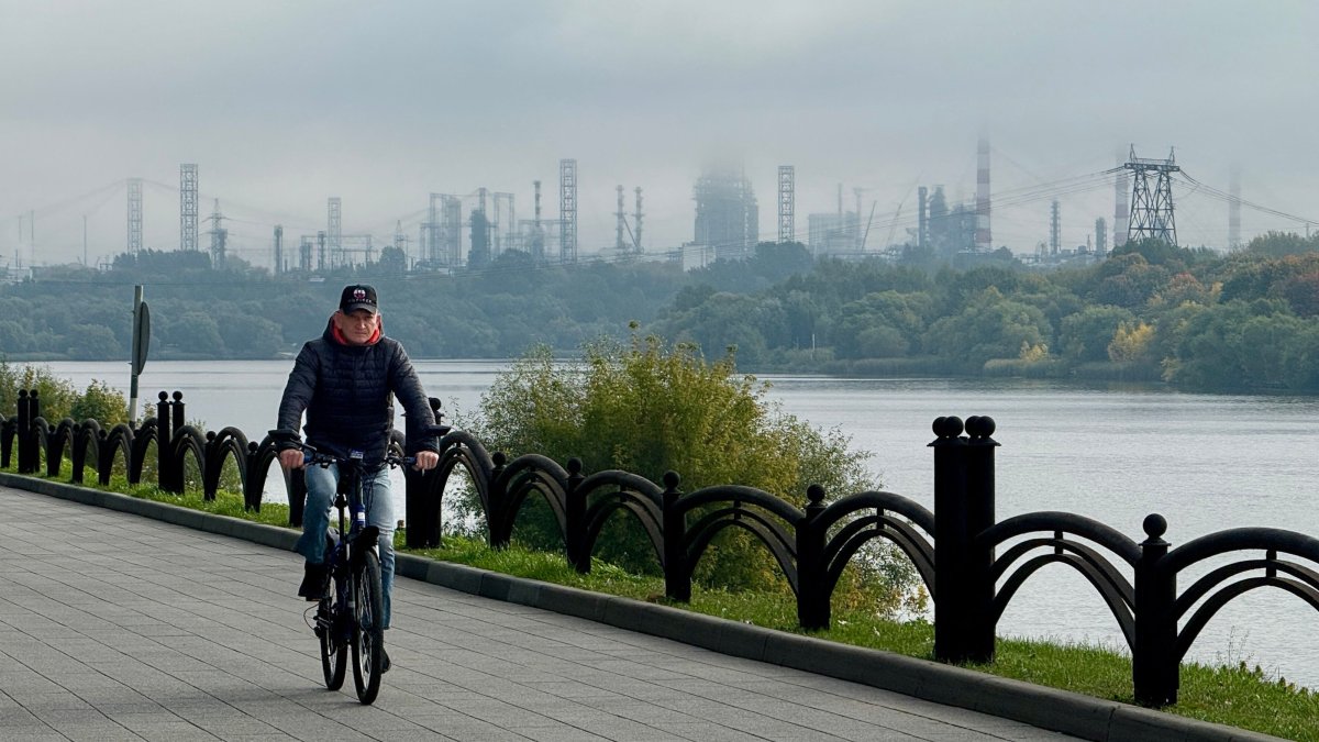 A man rides a bicycle on an embankment of the Moskva River, with the Russian oil producer Gazprom Neft's Moscow oil refinery seen in the distance, on the south-eastern outskirts of Moscow, Russia, Sept. 20, 2026. (AFP Photo)