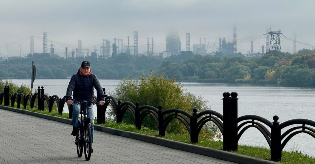 A man rides a bicycle on an embankment of the Moskva River, with the Russian oil producer Gazprom Neft's Moscow oil refinery seen in the distance, on the south-eastern outskirts of Moscow, Russia, Sept. 20, 2026. (AFP Photo)