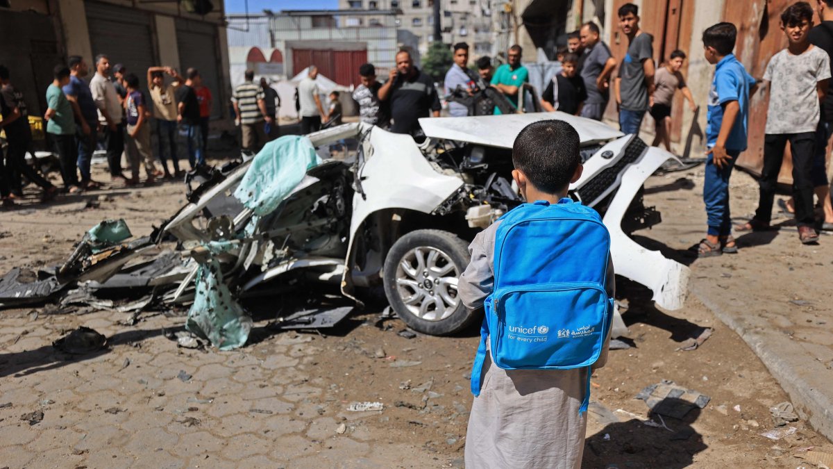 A Palestinian boy carrying UNICEF bag, looks at the wreckage of a car after it was destroyed in Israeli strike at the Tuffah neighborhood of Gaza City, Palestine, Oct. 13, 2026. (AFP Photo)