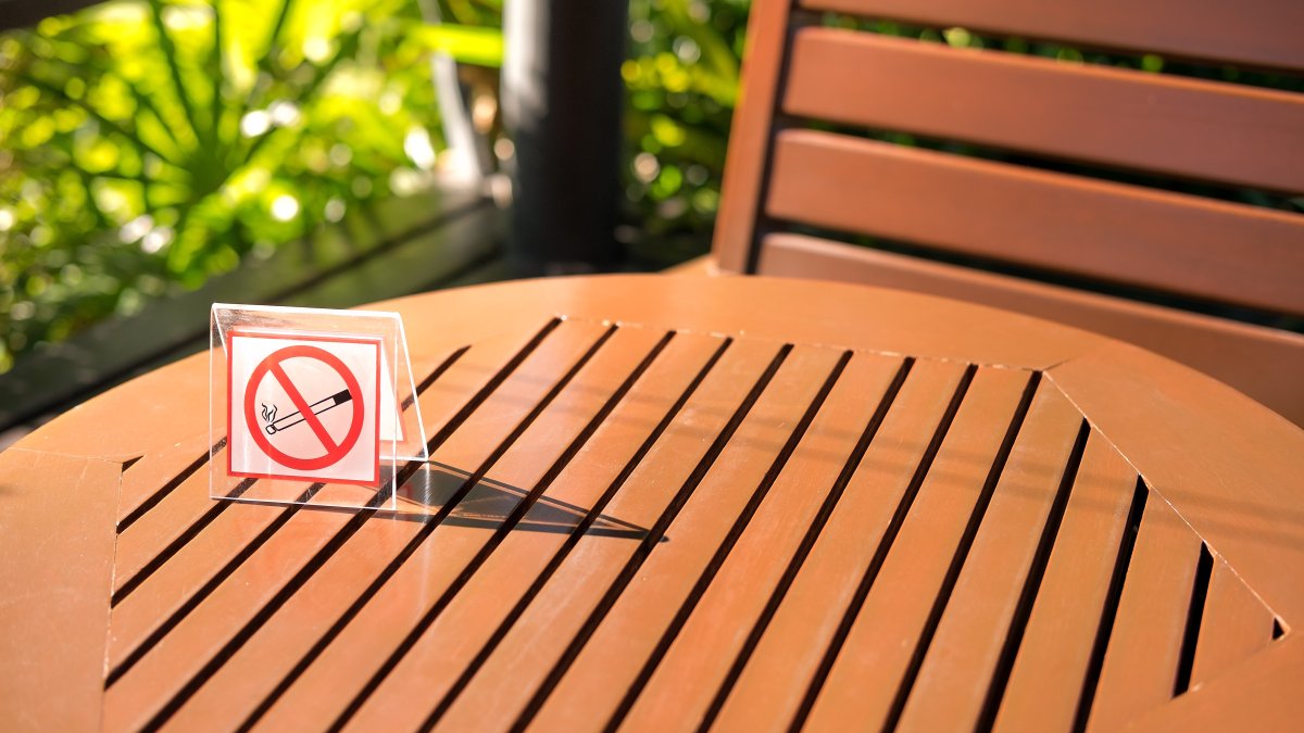 A no-smoking sign sits on a wooden table in a garden. (Shutterstock Photo)