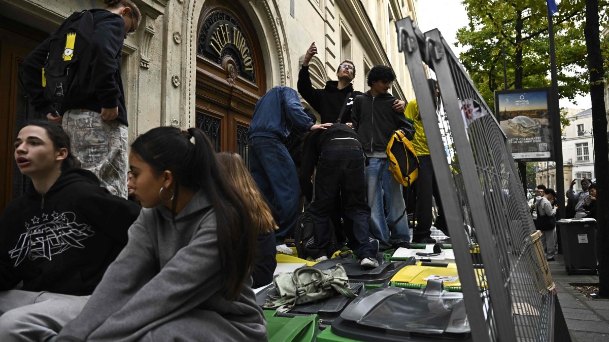 Youth climb on trash cans as students block the entrance of Turgot high school as part of a nationwide student movement to demand better classroom conditions in Paris, France, Oct. 14, 2026. (AFP Photo)