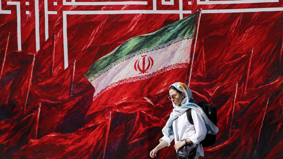 A woman walks past a mural in Tehran, Iran, Oct. 12, 2026. (AA Photo)