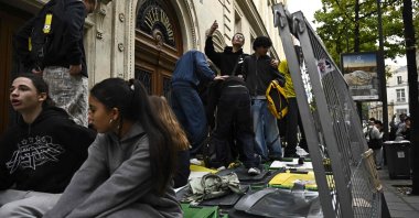 Youth climb on trash cans as students block the entrance of Turgot high school as part of a nationwide student movement to demand better classroom conditions in Paris, France, Oct. 14, 2026. (AFP Photo)