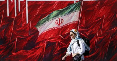 A woman walks past a mural in Tehran, Iran, Oct. 12, 2026. (AA Photo)