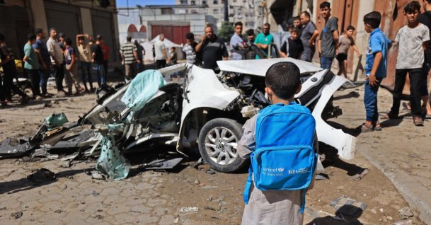 A Palestinian boy carrying UNICEF bag, looks at the wreckage of a car after it was destroyed in Israeli strike at the Tuffah neighborhood of Gaza City, Palestine, Oct. 13, 2026. (AFP Photo)