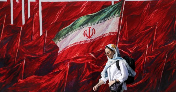 A woman walks past a mural in Tehran, Iran, Oct. 12, 2026. (AA Photo)