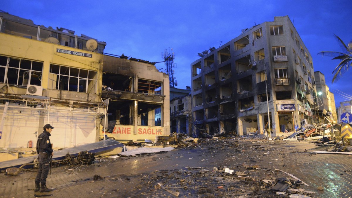 A police officer stands near damaged buildings on the street littered with debris from the explosions, Hatay, Türkiye, May 12, 2013. (AP Photo)