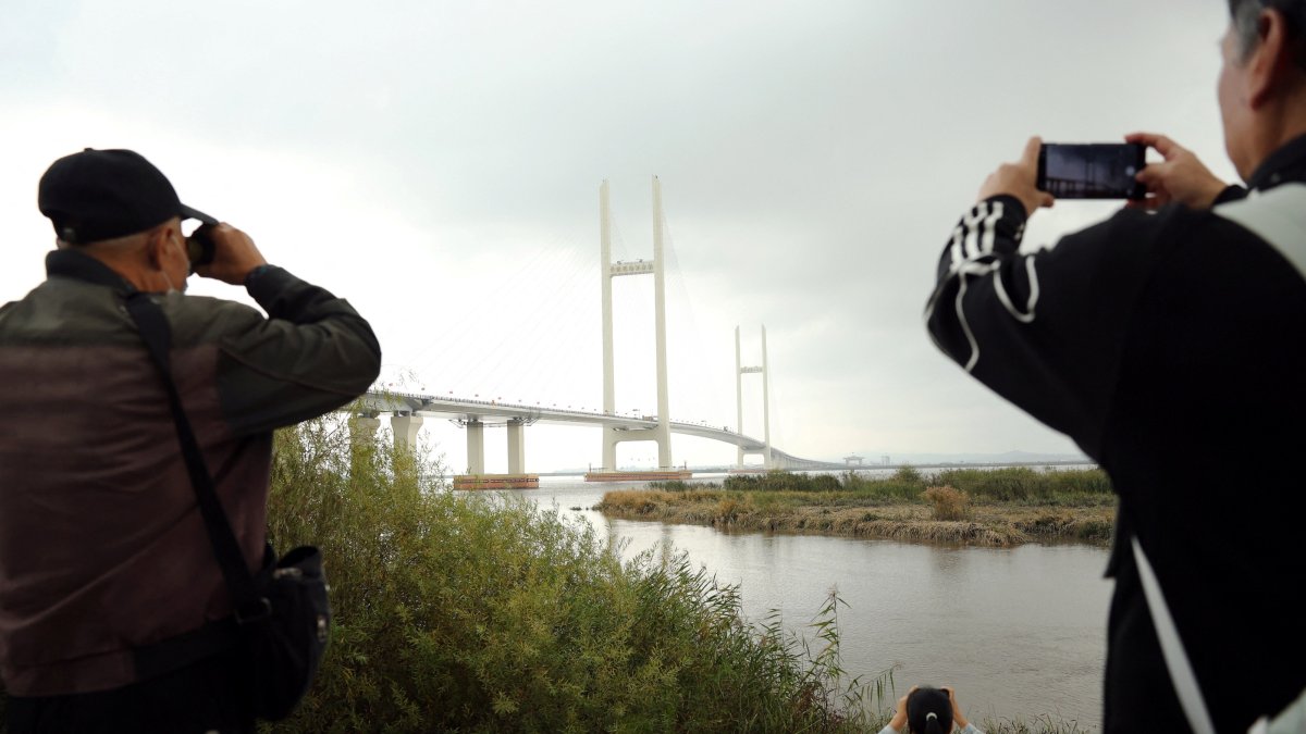 Residents take pictures of the newly opened New Yalu River Bridge, which connects China's Dandong New Zone and North Korea's Sinuiju, in Dandong, Liaoning province, China, Oct. 15, 2026. (Reuters Photo)