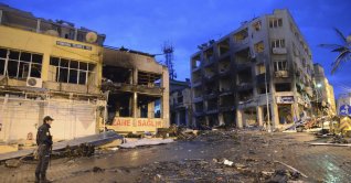 A police officer stands near damaged buildings on the street littered with debris from the explosions, Hatay, Türkiye, May 12, 2013. (AP Photo)