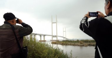 Residents take pictures of the newly opened New Yalu River Bridge, which connects China's Dandong New Zone and North Korea's Sinuiju, in Dandong, Liaoning province, China, Oct. 15, 2026. (Reuters Photo)