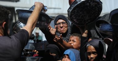 Nihaya Al-Masri, a 35-year-old displaced Palestinian woman from Beit Hanoun, waits to receive food for her family at a charity kitchen in Khan Younis, in the southern Gaza Strip, Oct. 6, 2026. (AFP File Photo)