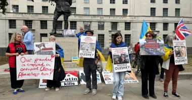 Larysa, 72, Oleshky resident who fled the town shortly after Russia's full-scale invasion of Ukraine in February 2022, holds posters as she participates in a rally demanding the establishment of a humanitarian corridor to evacuate Ukrainian civilians from her hometown, where her husband remains, amid Russia's attack on Ukraine, in London, Britain, Sept. 27, 2026. (Reuters Photo)