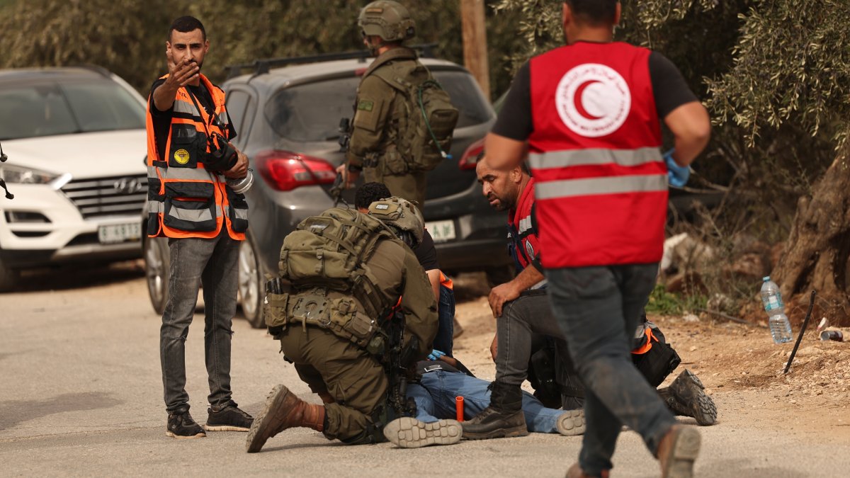 Israeli soldiers surround a Palestinian farmer who was shot by the Israeli army following a settlers' attack on families harvesting their olive trees in Abu Falah, West Bank, Oct. 16, 2026.  (EPA Photo)