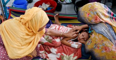 Relatives comfort six-year-old Istiyak Mahmud Zayan, who is receiving treatment on the floor of the overcrowded measles isolation ward of Shahid Shamsuddin Ahmed Hospital after developing symptoms of measles, Sylhet, Bangladesh, Sept. 12, 2026. (Reuters Photo)