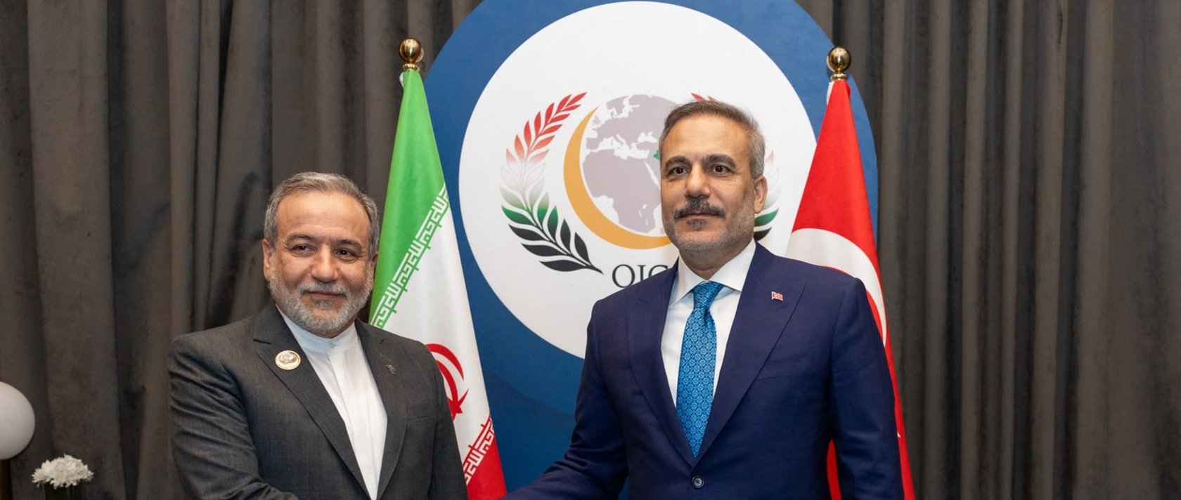 Foreign Minister Hakan Fidan shakes hands with Iranian Foreign Minister Abbas Araghchi on the sidelines of the 52nd Session of the Council of Foreign Ministers (CFM) of the Organisation of Islamic Cooperation (OIC) in Baghdad. (Photo by Turkish Foreign Ministry Press Service via AFP)