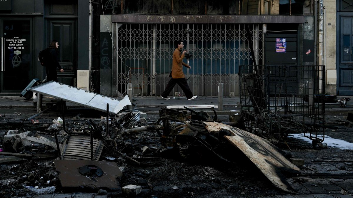 Pedestrians walk past damages and burnt down furniture, in central Bordeaux, southwestern France, Oct. 18, 2026. (AFP Photo)