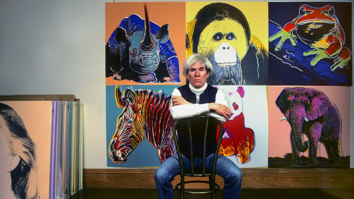 American Pop artist Andy Warhol sits in front of several paintings in his "Endangered Species" series at his studio, the Factory, Union Square, New York, U.S., April 12, 1983. (Getty Images Photo)