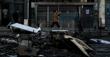 Pedestrians walk past damages and burnt down furniture, in central Bordeaux, southwestern France, Oct. 18, 2026. (AFP Photo)