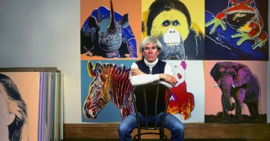 American Pop artist Andy Warhol sits in front of several paintings in his "Endangered Species" series at his studio, the Factory, Union Square, New York, U.S., April 12, 1983. (Getty Images Photo)