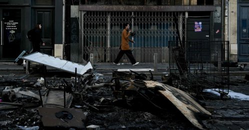 Pedestrians walk past damages and burnt down furniture, in central Bordeaux, southwestern France, Oct. 18, 2026. (AFP Photo)