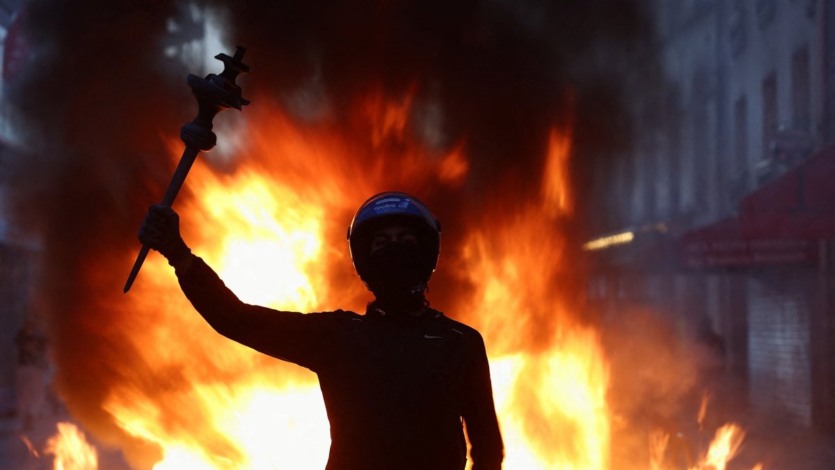A person raises their arm during civil unrest, the day after a national day of demonstrations against the cost of living and rising fuel prices, in Paris, France, Oct. 18, 2026. (Reuters Photo)
