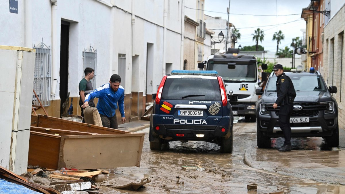 A police car patrols along a mud-covered street following floods caused by torrential downpours in Els Poblets, eastern Spain, Oct. 19, 2026. (AFP Photo)
