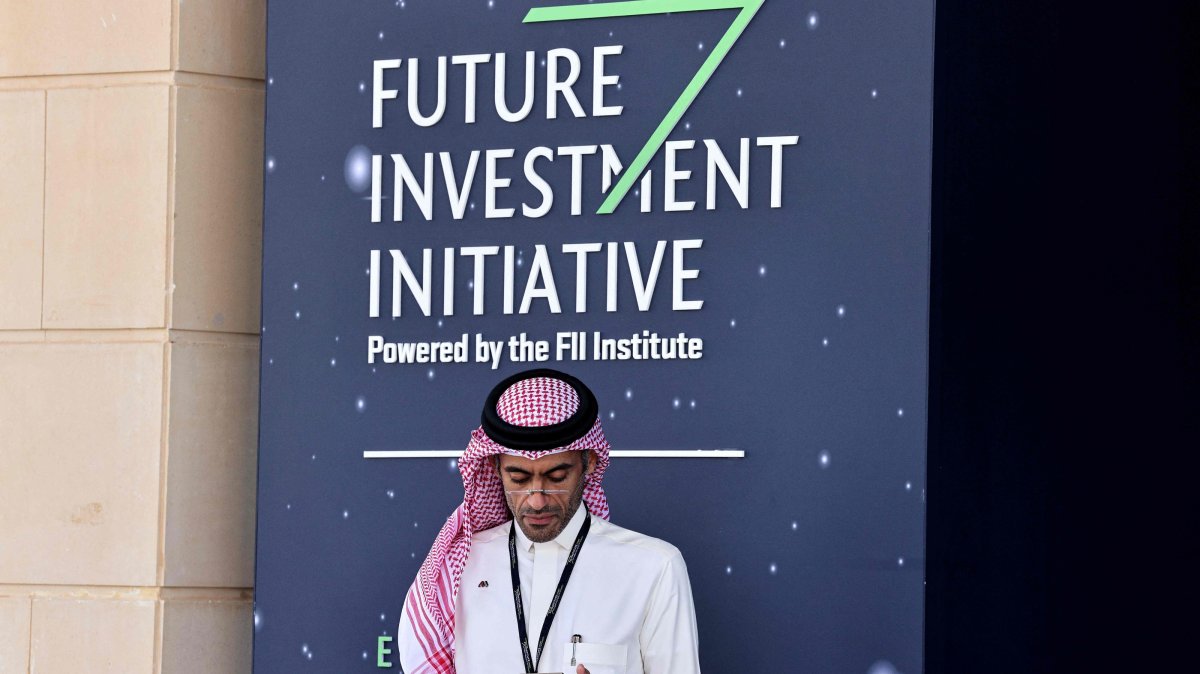 A Saudi man looks at his mobile phone as he attends the opening ceremony of the Future Investment Initiative (FFI) in Riyadh, Saudi Arabia, Oct. 28, 2025. (AFP Photo)