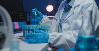 A scientist handles test tubes during laboratory research. (Shutterstock Photo)