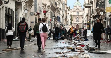 Pedestrians walk along a street covered in debris a day after nationwide protests against the "high cost of living" in Marseille, France, Oct. 18, 2026. (AFP Photo)