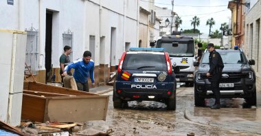 A police car patrols along a mud-covered street following floods caused by torrential downpours in Els Poblets, eastern Spain, Oct. 19, 2026. (AFP Photo)