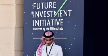 A Saudi man looks at his mobile phone as he attends the opening ceremony of the Future Investment Initiative (FFI) in Riyadh, Saudi Arabia, Oct. 28, 2025. (AFP Photo)