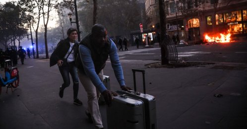 Tourists run with their luggage near Place de La Madeleine and a fire during a demonstration to protest against the "high cost of living" in Paris, France, Oct. 17, 2026. (AFP Photo)
