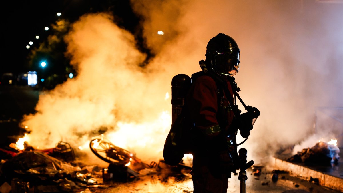A French firefighter responds to a street barricade burning, as clashes between riot police and demonstrators continue for the second day during nationwide protests against the high cost of living, Paris, France, Oct. 18, 2026. (EPA Photo)