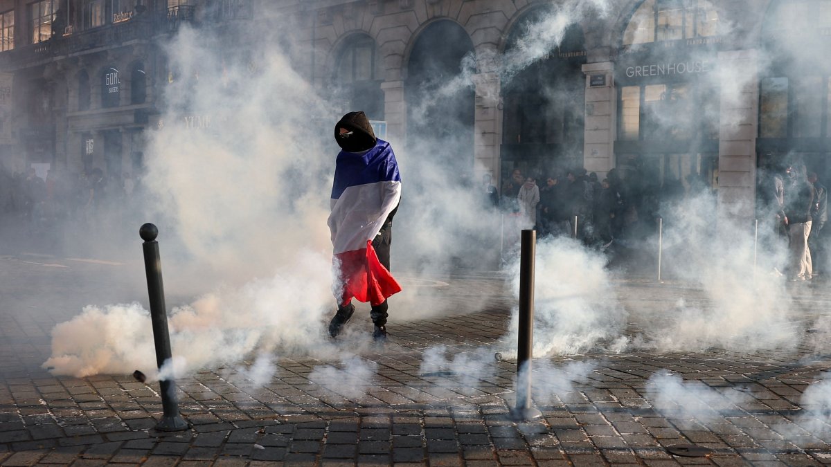 A protester, wrapped in a flag of France, stands in the smoke at Place de l'Opera during ongoing protest action against the "high cost of living", in Lille, northern France, Oct. 17, 2026. (AFP Photo)