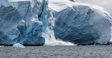 A giant chunk of ice breaking away from an ice sheet in Graham Passage, near Charlotte Bay, Antarctic Peninsula, Antarctica. (Shutterstock Photo)