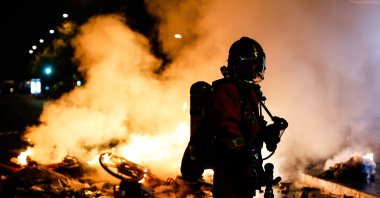 A French firefighter responds to a street barricade burning, as clashes between riot police and demonstrators continue for the second day during nationwide protests against the high cost of living, Paris, France, Oct. 18, 2026. (EPA Photo)