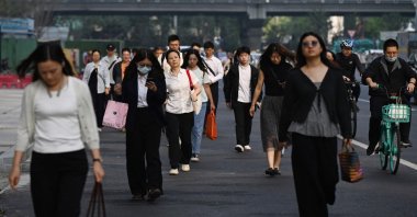 Office workers walk to their buildings in the central business district, Beijing, China, Sept. 23, 2026. (AFP Photo)
