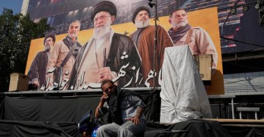 A man talks on his cellphone while sitting on a motorbike in front of a billboard showing portraits of the late Iranian Supreme Leader Ayatollah Ali Khamenei (C) late leaders of Lebanon's Hezbollah group Hassan Nasrallah (2nd R) and Hashem Safieddine (L) late commander of Iran's Revolutionary Guard Quds Force, Gen. Qassem Soleimani (2nd L) and a top commander of the guard Gen. Abbas Nilforoushan, who were killed in Israeli and U.S. strikes, at the Islamic Revolution Square in Tehran, Iran, Oct. 12, 2026. (AP Photo)