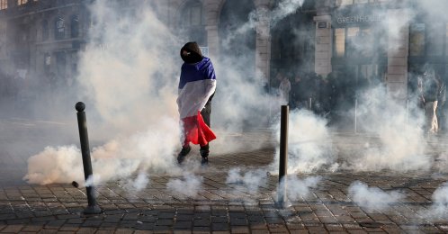 A protester, wrapped in a flag of France, stands in the smoke at Place de l'Opera during ongoing protest action against the "high cost of living", in Lille, northern France, Oct. 17, 2026. (AFP Photo)