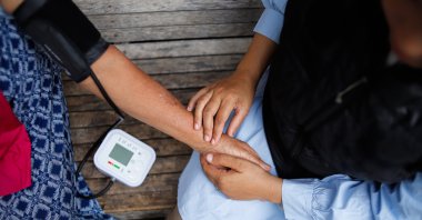 A health care worker checks the blood pressure of an elderly woman in a rural area during a medical visit. (Shutterstock Photo)