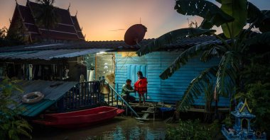 A father removes a flotation vest worn by his daughter in front of their flooded home in Bang Ban district in Ayutthaya, central Thailand, Oct. 7, 2026. (AFP Photo)