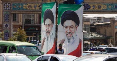 A police officer monitors traffic as he stands under portraits of Iran's supreme leader, Ayatollah Mojtaba Khamenei in Tehran, Oct. 21, 2026. (AFP Photo)