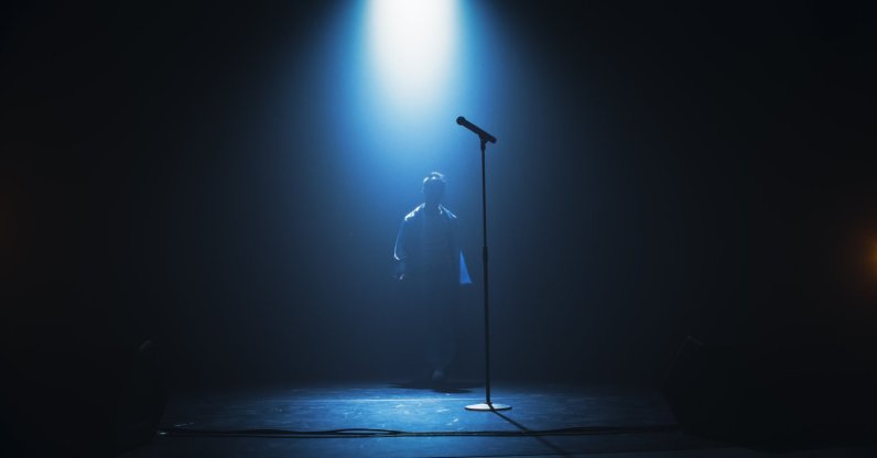A silhouette of a singer on stage under the spotlight. (Shutterstock Photo)